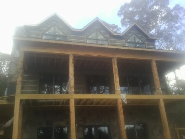 Dormers and porch framing on a large log home under construction — Roof Coating work by our crew in Islip