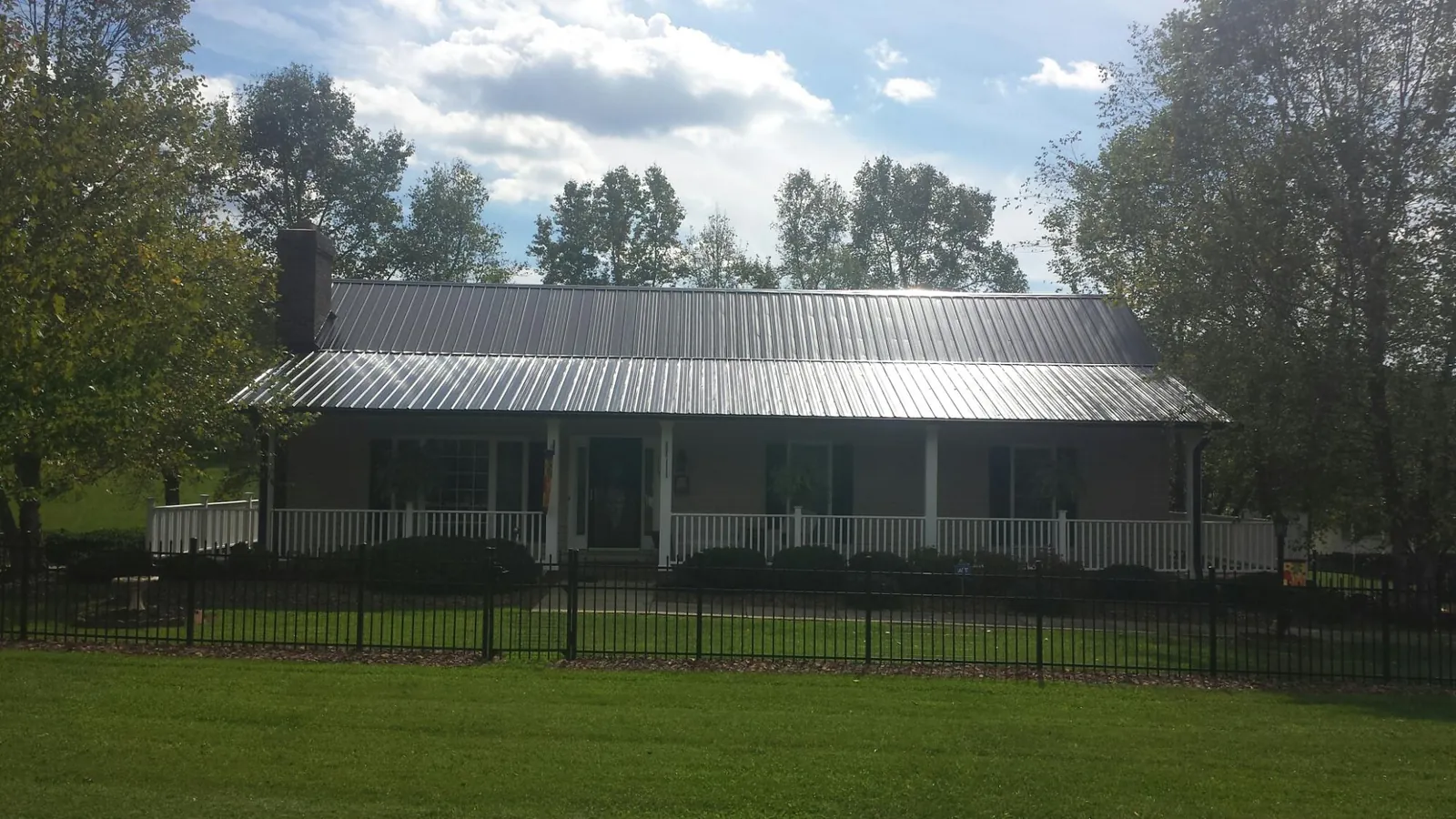 Gray metal roof on a brick ranch with a full width front porch — Gutter Guard Installation work by our crew in Islip